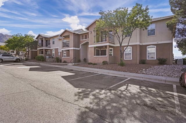 Exterior view of apartment buildings with parking lot in foreground.