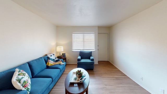 Living room with a blue sofa and armchair, coffee table, and window.