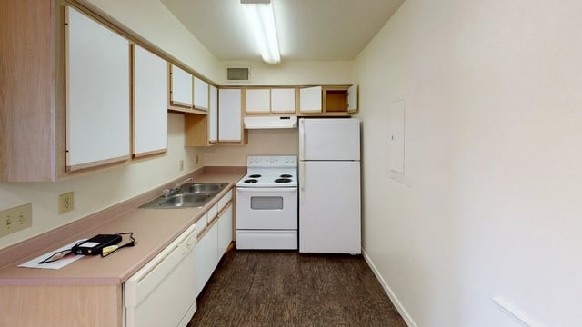 Kitchen with white appliances, light wood cabinets, and laminate flooring