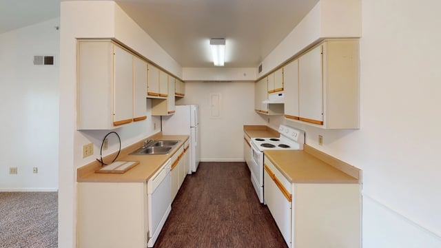Kitchen with white cabinets, countertops, white appliances, and dark wood floor.