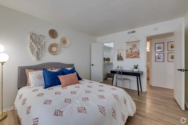 Bedroom with a queen-size bed, desk, and closet.