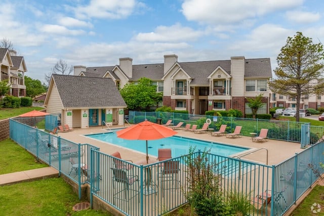 Apartment complex swimming pool with lounge chairs and umbrellas.