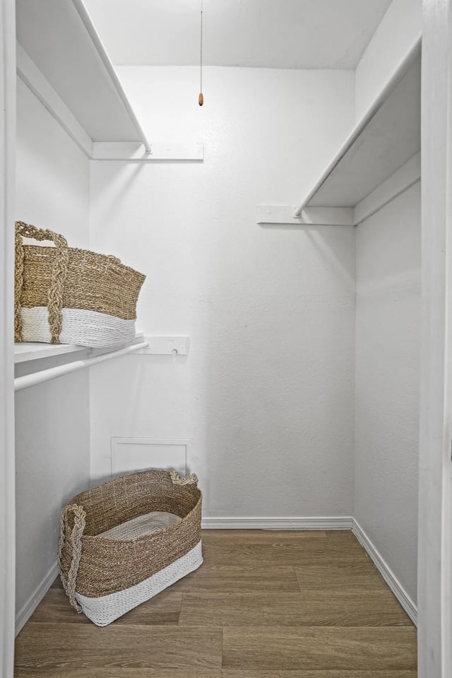 White walk-in closet with shelves and woven baskets on racks.