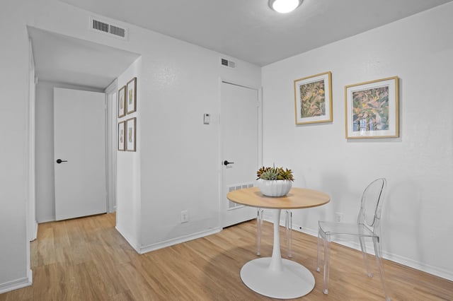 Dining area with a round table, clear chair, and artwork.