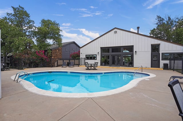 Outdoor swimming pool with lounge chairs and a building in the background.