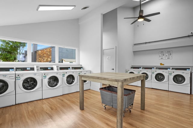 Laundry room with multiple washing machines, dryers, and a folding table.