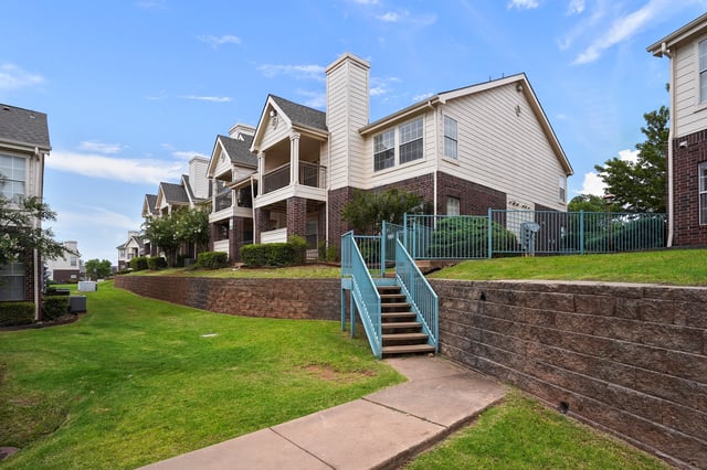 Exterior view of apartment buildings with green lawns and brick accents.