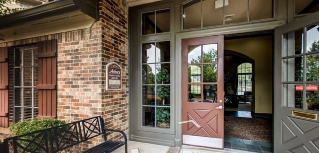 Building entrance with brick exterior, brown shutters, and an open door.