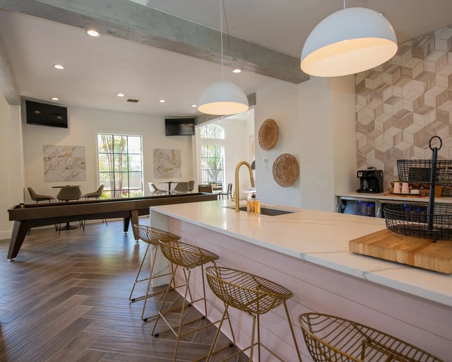 A kitchen with a white counter and a bar area with stools.