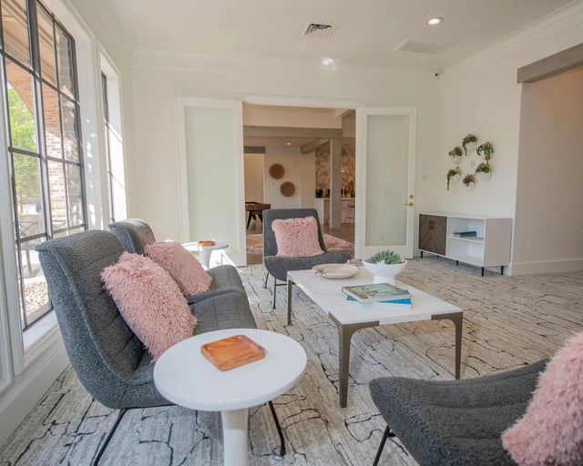 A living room with a grey couch, a white coffee table, and a pink cushion.
