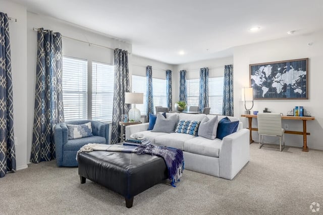Spacious living room with a sectional sofa, ottoman, armchair, and desk.