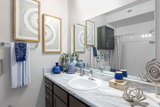 Bathroom vanity with marble countertop, white sink, chrome faucet, and decorative items.