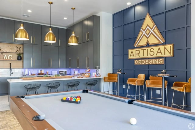 Billiard table and bar area in community lounge with Artisan Crossing logo on wall.