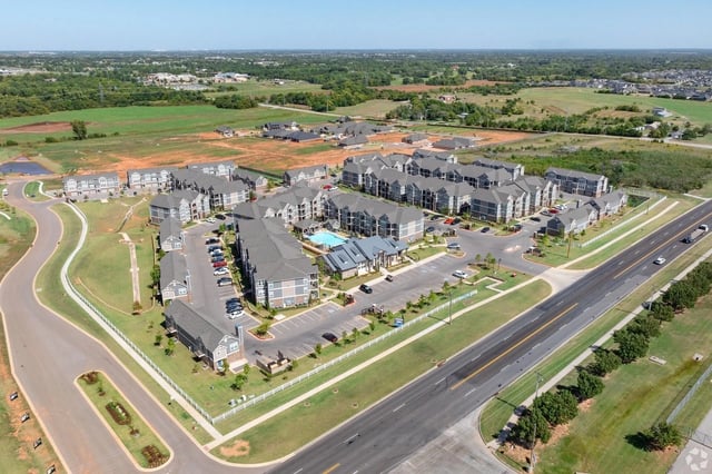Aerial view of apartment complex with pool and surrounding landscape.