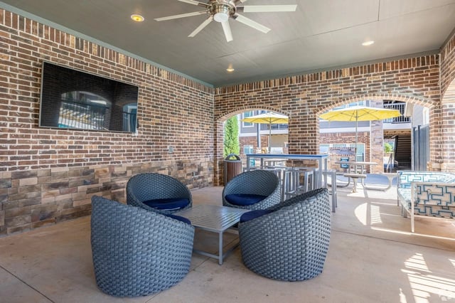 Outdoor lounge area with seating and a TV.