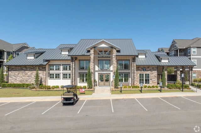 Exterior of a modern apartment building with a golf cart parked in the lot.