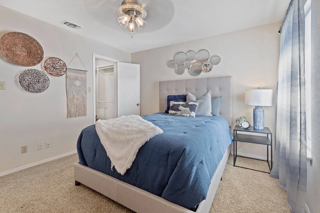 A bedroom with a blue bedspread and a white blanket.