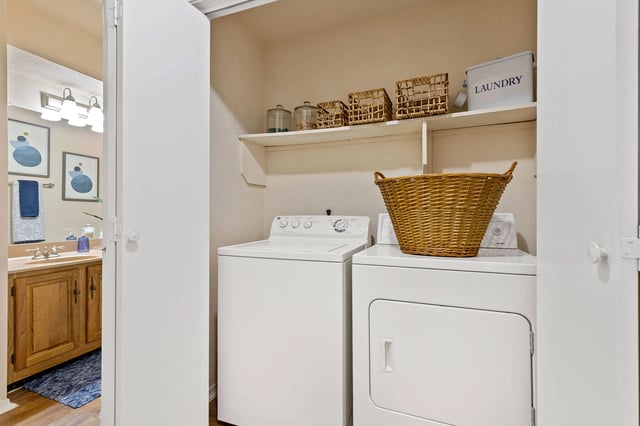 A laundry room with a washer and dryer and a basket on top of the dryer.