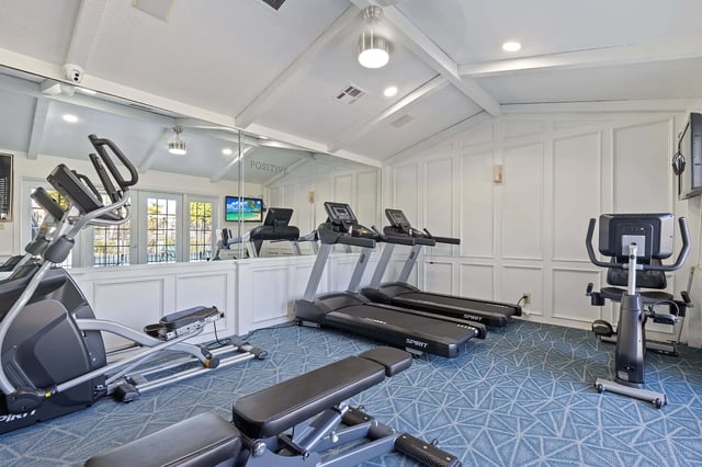 Gym with treadmills, elliptical, stationary bike, and weight bench