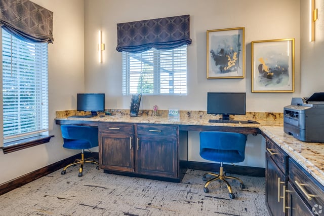 Shared community office area with two desks, monitors, and a printer.