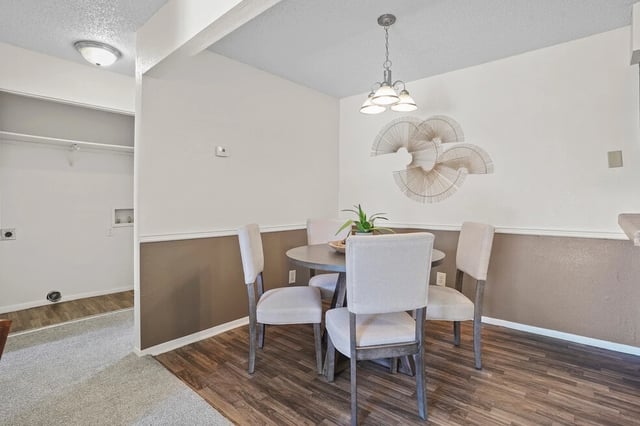 Dining area with a round table and four chairs, adjacent to a laundry area.