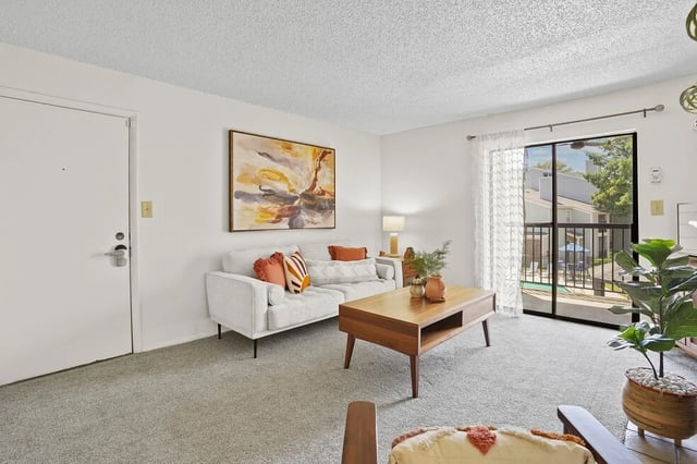 Living room with white sofa, wooden coffee table, and view of the pool area.