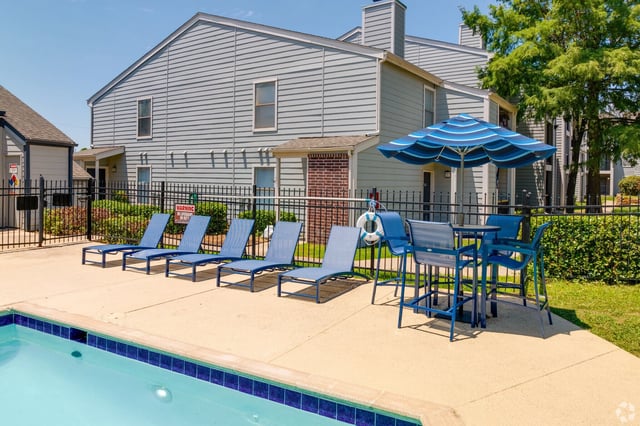 Outdoor swimming pool with lounge chairs and a table with umbrella.