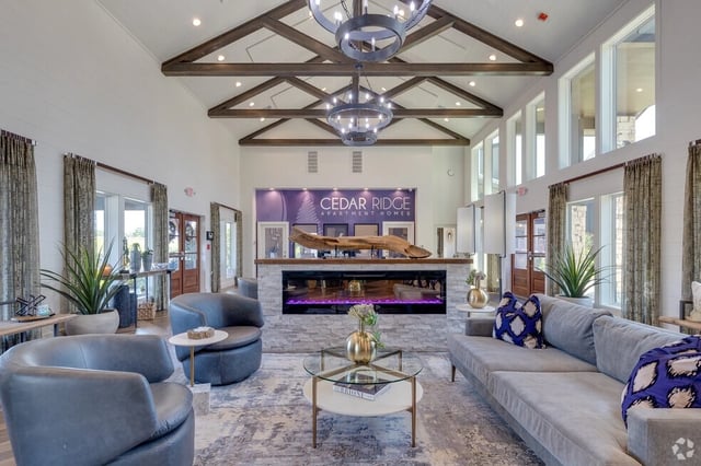 The spacious clubhouse lobby of Cedar Ridge Apartment Homes features a modern fireplace and comfortable seating areas.