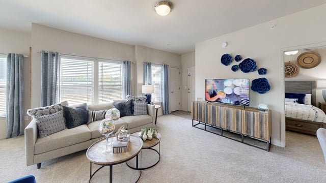Living room with a sofa and coffee table, and a glimpse of a bedroom.