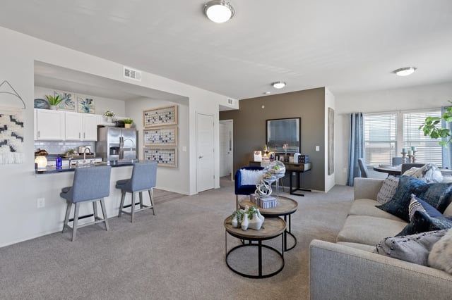 A living room with a grey couch and a round table in the middle.