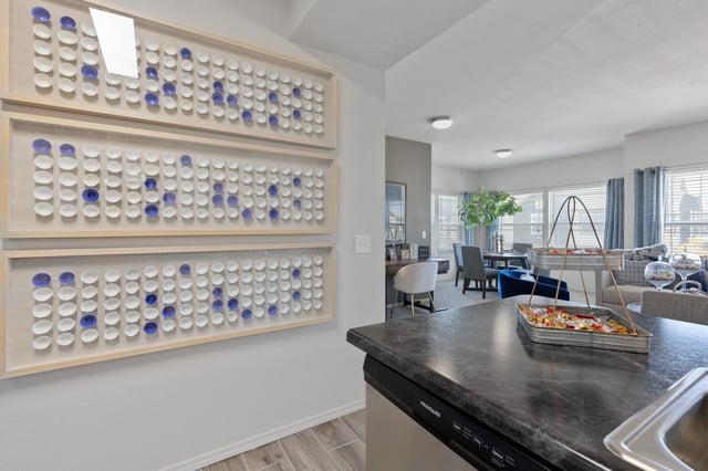 A kitchen with a black counter top and a wall with blue and white tiles.