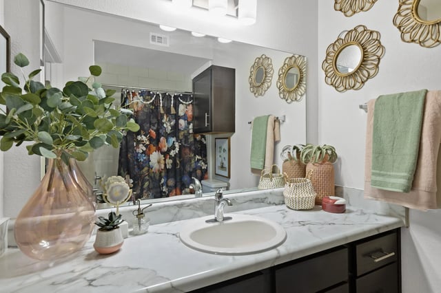 A bathroom with a white counter top and a pink vase.