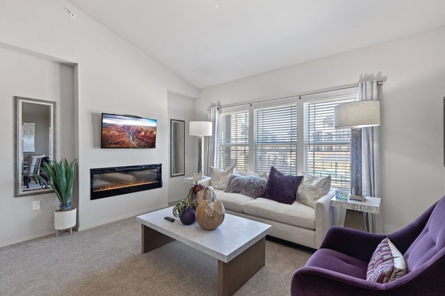A modern living room with a purple chair and a fireplace.