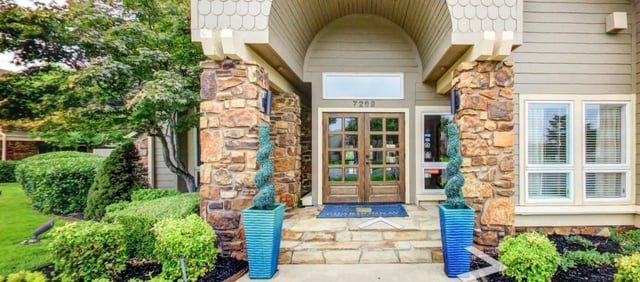 Building entrance with stone pillars, double doors, and landscaping.