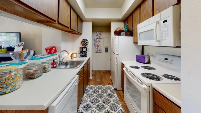 Kitchen with white countertops, wooden cabinets, and white appliances.