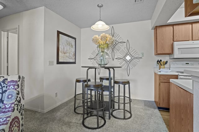 Dining nook with a tall, round table and four metal stools in a kitchen area.