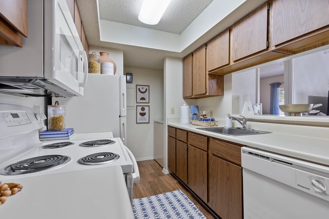 Updated kitchen with white appliances, wood cabinets, and laminate flooring.