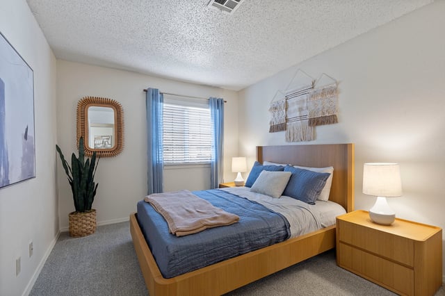Bedroom with a queen-size bed and blue bedding, bedside tables, and decor.