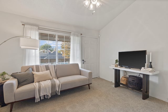 Living room with a gray sofa, throw blankets, and a television on a console table.