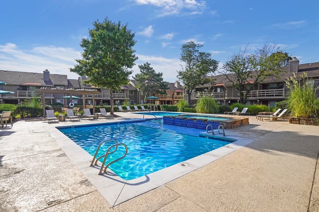 Outdoor swimming pool with lounge chairs and surrounding apartment buildings.