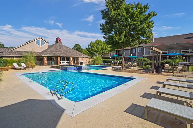 Resort-style swimming pool with lounge chairs and seating areas under umbrellas.