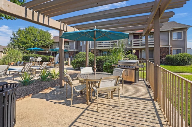 Outdoor dining area with grill and patio furniture near a swimming pool.