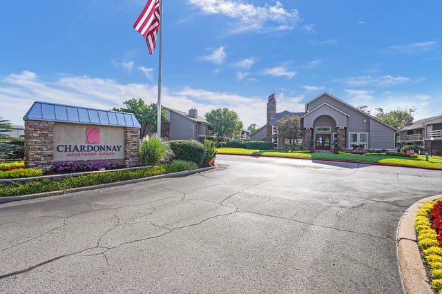 Chardonnay Apartment Homes monument sign and building exterior with American flag.