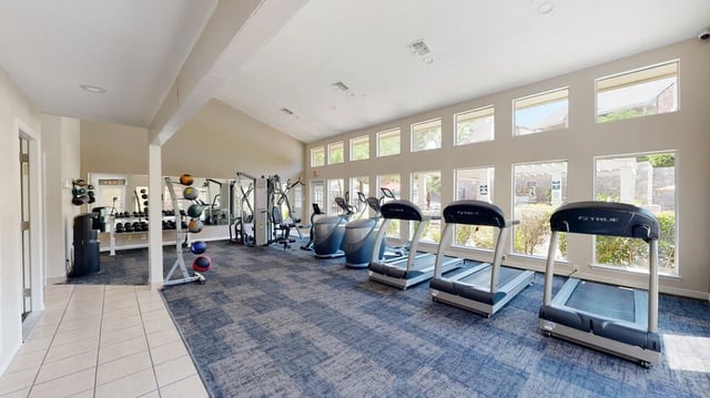Fitness center with treadmills, elliptical machines, weight racks, and medicine balls.