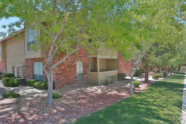 Exterior view of brick apartment buildings with trees and landscaping.