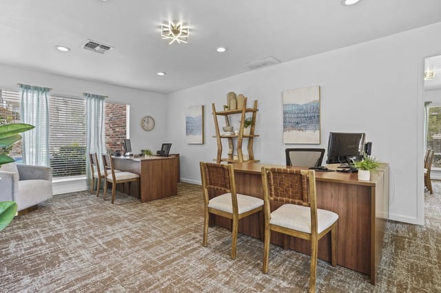 Leasing office in a bright community space with desks, computers, and seating.