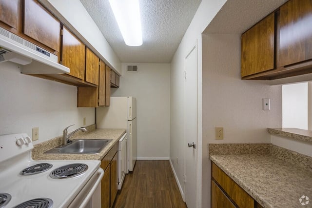 Kitchen with wood cabinets, granite countertops, white appliances, and wood-look flooring.