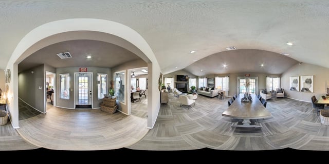 Lobby and lounge area of apartment complex with seating, a dining table, and fireplace.
