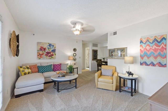 Living room with a sectional sofa, accent chair, coffee table, and dining area visible in the background.