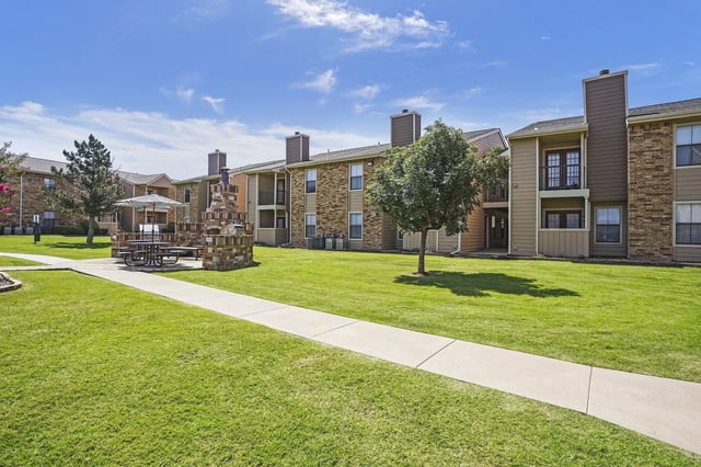 Apartment building exterior with picnic area and outdoor grill.